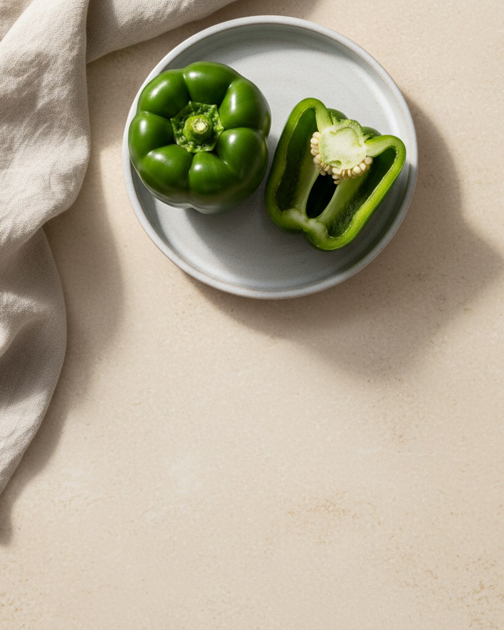 A whole green bell pepper with a cut half beside it