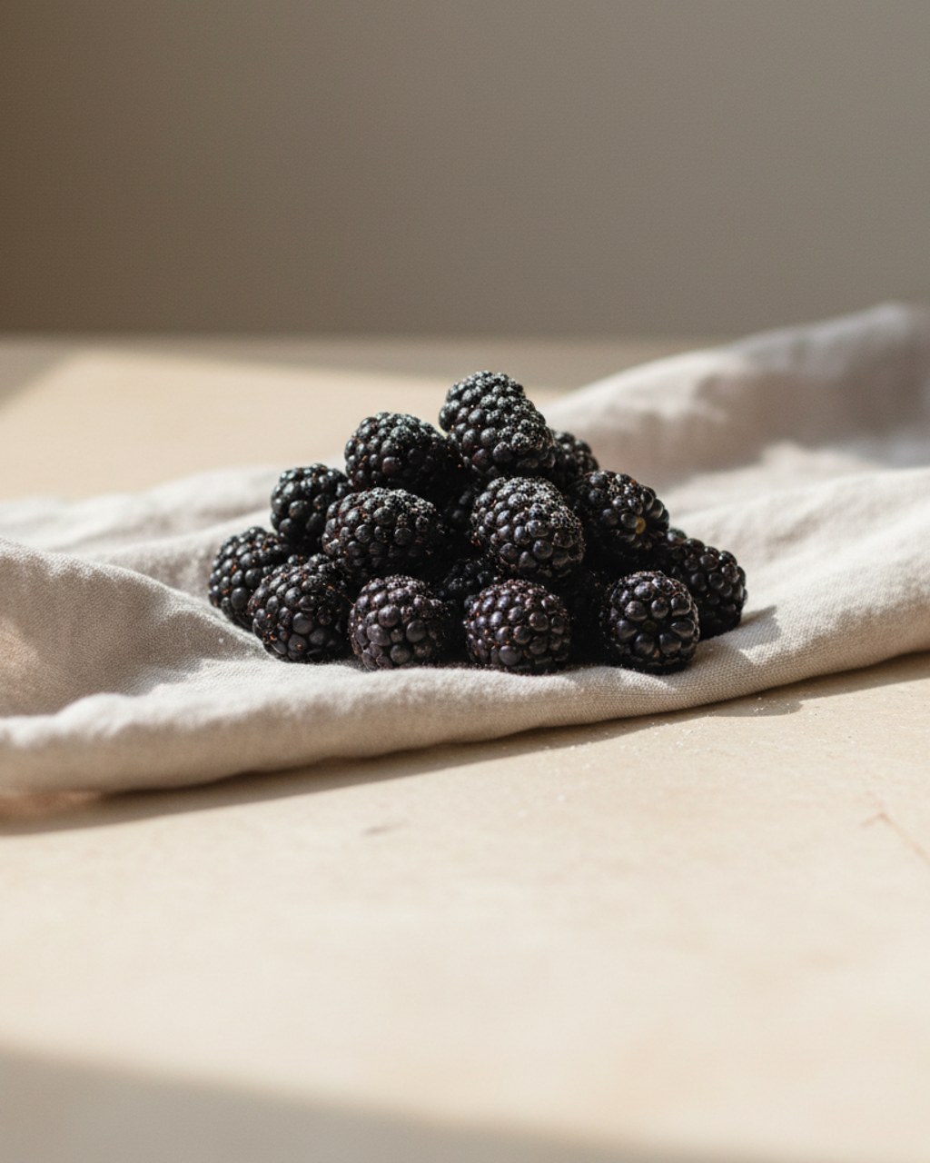A small pile of fresh ripe blackberries on a warm cream surface