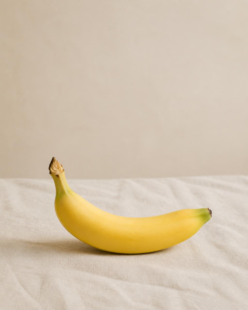 One firm slightly under-ripe banana on cream linen